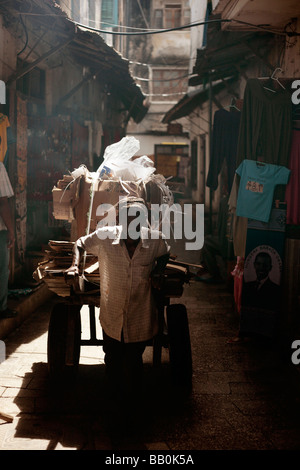 L'homme tirant une charrette à travers les rues de smokey de Stone Town à Zanzibar Banque D'Images