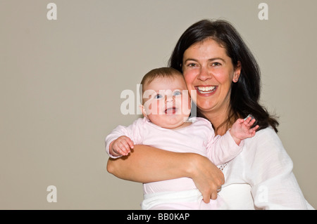 Close up portrait of horizontal d'un rire à l'âge de six mois, bébé fille ayant une accolade et certains d'temps avec sa fière maman Banque D'Images