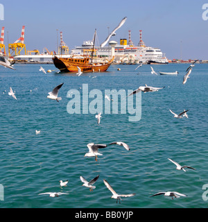 Muscat Dhow amarré dans le port de Muttrah en bord de mer avec Costa Bateau de croisière amarré à Port Sultan Qaboos au-delà des mouettes dans Vol Oman Golfe d'Oman Banque D'Images