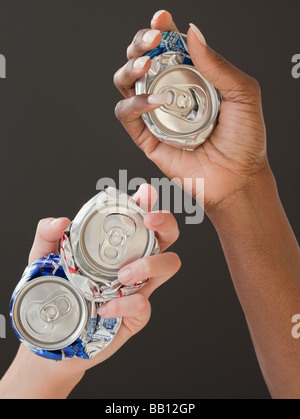 African and Caucasian woman holding canettes écrasées Banque D'Images