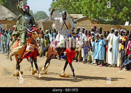 Cameroun, Pouss. Cavaliers d'Afrique un cheval de course sur une piste poussiéreuse devant un groupe d'autres cavaliers Banque D'Images