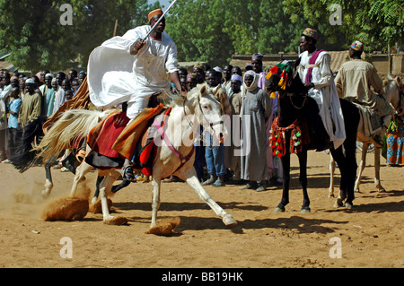 Cameroun, Pouss. Cavaliers d'Afrique un cheval de course sur une piste poussiéreuse devant un groupe d'autres cavaliers Banque D'Images