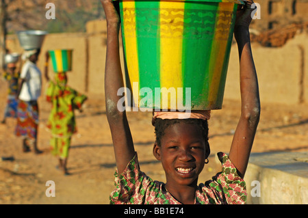 Le Mali, Pays Dogon. Portrait d'une jeune fille portant un bassin d'eau sur sa tête (RF) Banque D'Images