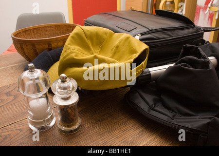 Sel et moulins à poivre, une casquette jaune, la vannerie un bol de fruits et d'autres choses sur une table en chêne Banque D'Images