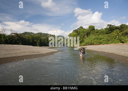 Randonnées d'une femme à travers une rivière dans le parc national de Corcovado, Costa Rica Banque D'Images