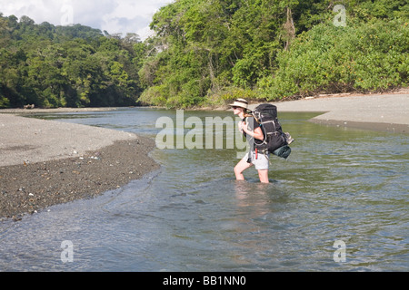 Randonnées d'une femme à travers une rivière dans le parc national de Corcovado, Costa Rica Banque D'Images