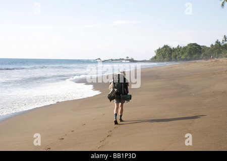 Une femme avec un sac à dos le long du littoral sablonneux fo du Parc national Corcovado, Costa Rica. Banque D'Images