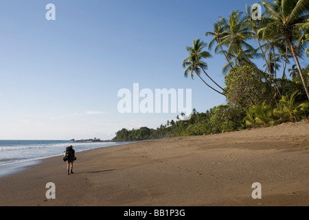 Une femme avec un sac à dos le long du littoral sablonneux fo du Parc national Corcovado, Costa Rica. Banque D'Images