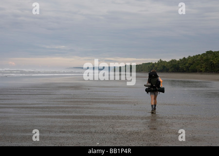 Une femme avec un sac à dos le long du littoral sablonneux fo du Parc national Corcovado, Costa Rica. Banque D'Images