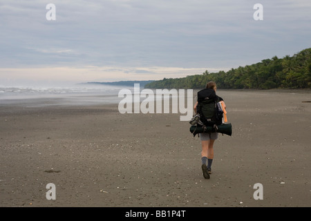 Une femme avec un sac à dos le long du littoral sablonneux fo du Parc national Corcovado, Costa Rica. Banque D'Images