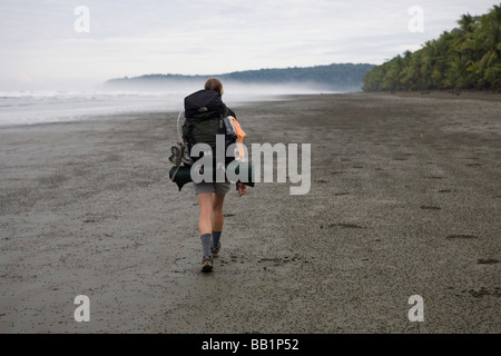 Une femme avec un sac à dos le long du littoral sablonneux fo du Parc national Corcovado, Costa Rica. Banque D'Images