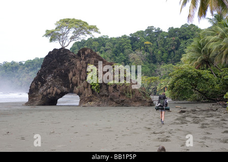 Une femme avec un sac à dos le long du littoral sablonneux fo du Parc national Corcovado, Costa Rica. Banque D'Images