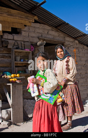 Jeune mère avec ses filles debout par leur adobe et connectez-vous accueil dans le village de Tarahumara San Alonso à Copper Canyon Banque D'Images