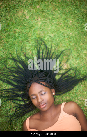 Femme avec des dreadlocks portant sur l'herbe au jardin, Pietermaritzburg, province de KwaZulu-Natal, Afrique du Sud Banque D'Images