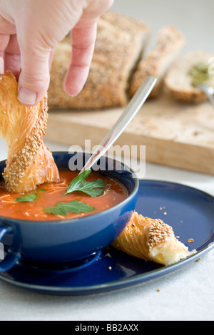 Délicieux bol de soupe de tomate et de trempage à la main avec du pain un peu de mouvement dans la main Banque D'Images