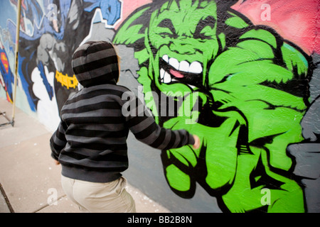 Boy running jusqu'à une peinture de la carcasse incroyable sur un mur Banque D'Images