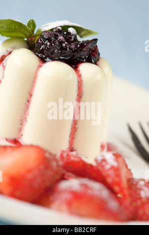 Le panna cotta dessert surmontée de black berry sauce et fraises Banque D'Images