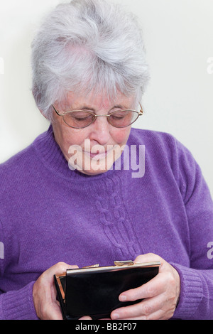 Close up d'un pensionné britannique sans le sou à la recherche dans un sac à main dans ses mains avec expression en temps d'austérité. Angleterre Royaume-uni Grande-Bretagne Banque D'Images