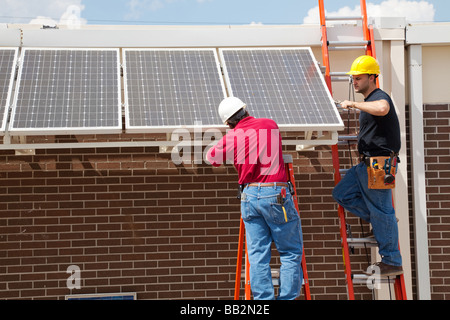 Deux électriciens l'installation de panneaux solaires sur un bâtiment Banque D'Images