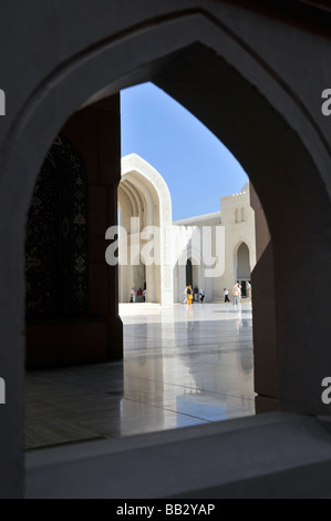 Arche intérieure encadrant une partie de superbes bâtiments religieux blancs extérieurs dans la Grande Mosquée Sultan Qaboos le jour du ciel bleu Mascate Oman moyen-Orient Asie Banque D'Images