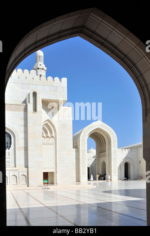 Arche intérieure encadrant une partie de superbes bâtiments religieux blancs extérieurs dans la Grande Mosquée Sultan Qaboos le jour du ciel bleu Mascate Oman moyen-Orient Asie Banque D'Images