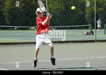 Un garçon de neuf ans à jouer au tennis Banque D'Images