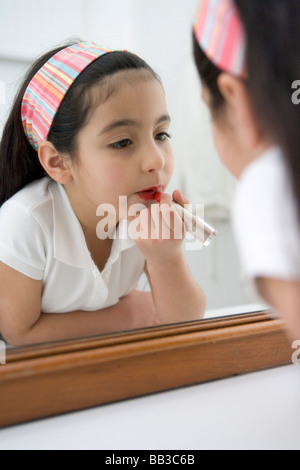 Petite fille de mettre du rouge à lèvres Banque D'Images