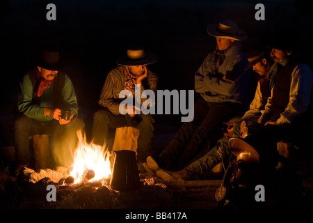 USA, Ohio, Seneca, Ranch Ponderosa. Cowboys assis autour d'un feu de camp. Banque D'Images