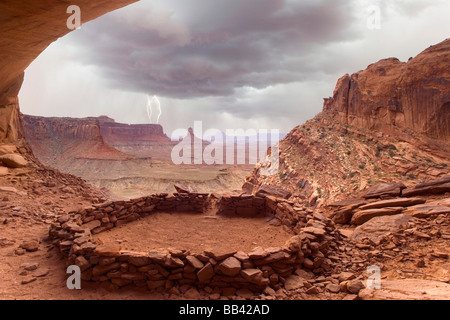 USA, Utah, Canyonlands National Park. Voir d'Anasazi ruine avec la foudre et tonnerre en arrière-plan. Banque D'Images