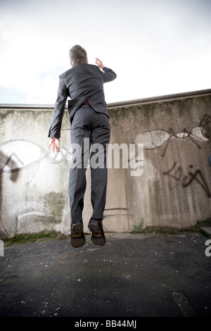 Un homme dans une entreprise passe à voir sur un mur de béton en Hambrug, Allemagne. Banque D'Images