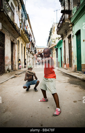 Garçon jouant au baseball dans la rue avec un balai bat, La Havane, Cuba. Banque D'Images