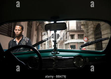 Propriétaire de voiture vu à travers le pare-brise de la vieille Chevrolet, La Havane, Cuba. Banque D'Images