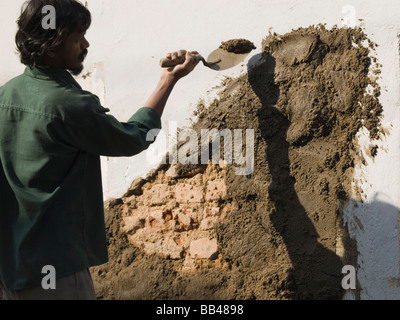 L'homme travaillant sur un chantier de construction s'applique à un mur de ciment à Bangalore, Karnataka, Inde Banque D'Images