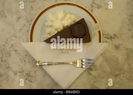 Une tranche de gâteau original Sacher- Torte avec crème fouettée à l'hôtel Sacher, Vienne, Autriche. Banque D'Images