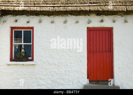 L'Europe, l'Irlande, Gleann Cholm Chille. Détails d'un cottage au toit de chaume avec une porte rouge. Banque D'Images