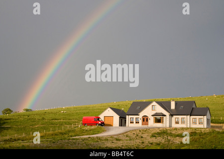 L'Europe, l'Irlande, le Donegal. Arcs arc-en-ciel de l'après-midi à travers le ciel sur une maison à la campagne. Banque D'Images