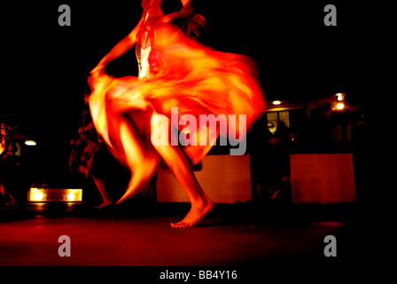 GUAM. Femme polynésienne danse et de tordre sa longue jupe rouge avec ses mains Banque D'Images