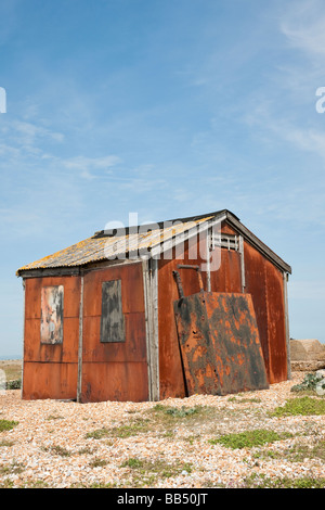 Abandonné old rusty hangar avec un premier plan de gravier contre le ciel bleu Banque D'Images