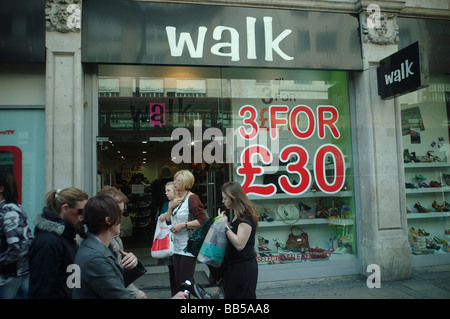 Shoppers femme devant une succursale de marche qui a un trois pour offrir trente livres sur Oxford Street Londres Banque D'Images