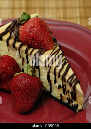 Cheesecake arrosé avec du chocolat et garnie de fraises Banque D'Images