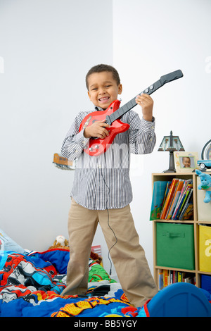 Mixed Race boy playing toy guitar Banque D'Images