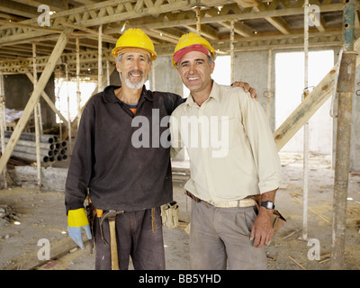 Les travailleurs hispaniques hugging at construction site Banque D'Images