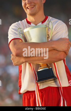 Le joueur de soccer masculin triomphalement hugging trophy Banque D'Images