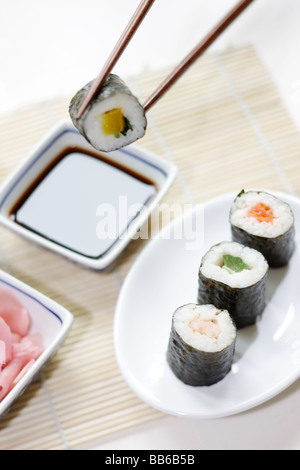 De style japonais, sushi de légumes assortis enveloppée de riz collant et d'algues détenues par les baguettes avec aucun peuple Banque D'Images