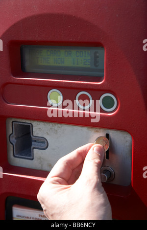 Man putting livre pièce dans payer et afficher machine parking au Royaume-Uni Banque D'Images