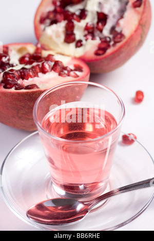 Pmegranate réduit de moitié sur fond blanc avec verre de jus de grenadine Banque D'Images