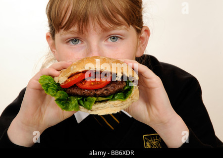 Manger une écolière beefburger avec une salade saine du remplissage Banque D'Images