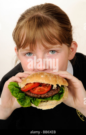 Manger une écolière beefburger avec une salade saine du remplissage Banque D'Images