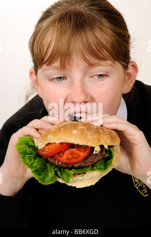 Manger une écolière beefburger avec une salade saine du remplissage Banque D'Images