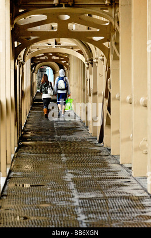 Passerelle piétonne sur le pont de haut niveau entre Newcastle et Gateshead. Jeune couple à s'éloigner de l'appareil photo Banque D'Images